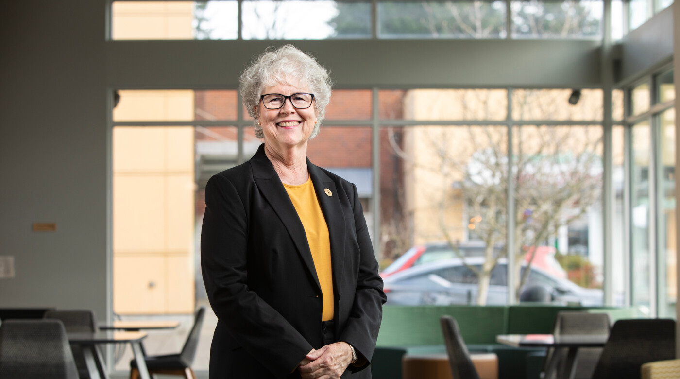 New dean looks into the camera and smiles while standing in a classroom.