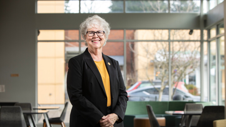 New dean looks into the camera and smiles while standing in a classroom.