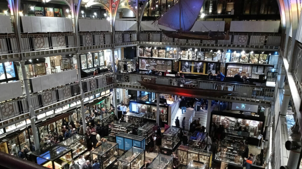 A full house for a museum expo at the University of Oxford. Hundreds of people look at many exhibits - photo shows two levels of the museum through an open lobby.