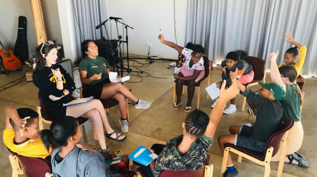 Jessa laughing while sitting with Namibian students in a circle of chairs