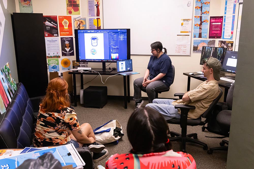 Ivan Wilson, Art Director for the student run creative agency Impact, leads a critique with the staff of designers, Tuesday, May 6, 2025, in the AUC at PLU. (PLU Photo / Sy Bean) Ivan Wilson, Art Director for the student run creative agency Impact, leads a critique with the staff of designers, Tuesday, May 6, 2025, in the AUC at PLU. (PLU Photo / Sy Bean)