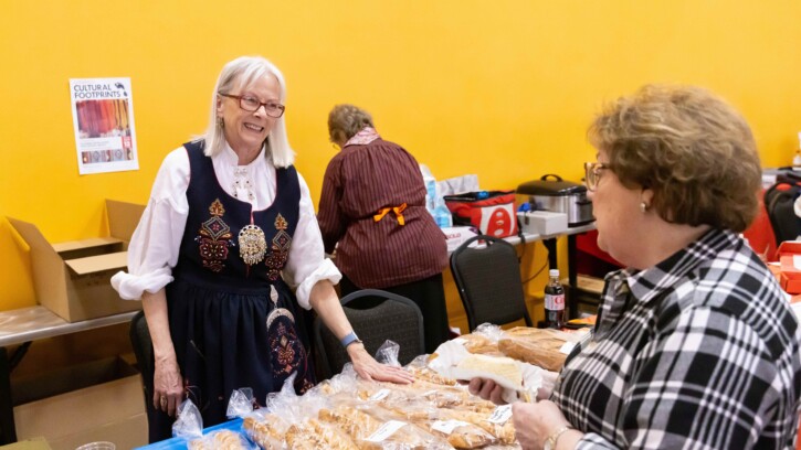 A smiling woman volunteering for an event at the SCC speaks to an attendee.