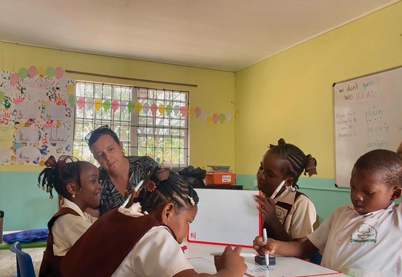 Amy Siegesmund sitting with students and helping them with school work