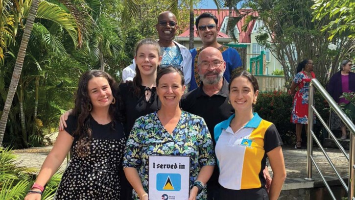 Amy Siegesmund and several other people standing on stairs and smiling while she served in St. Lucia during her Peace Corps trip