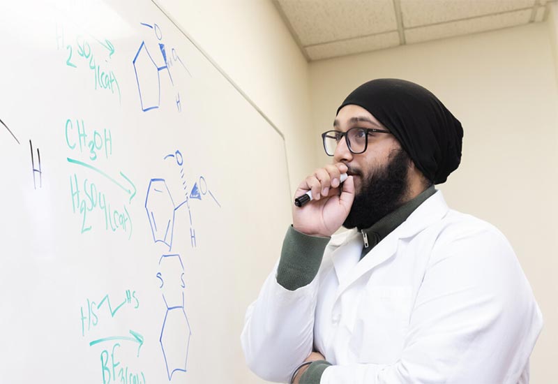 Chemistry and Religion double major Justin Singh looks at a whiteboard full of equations