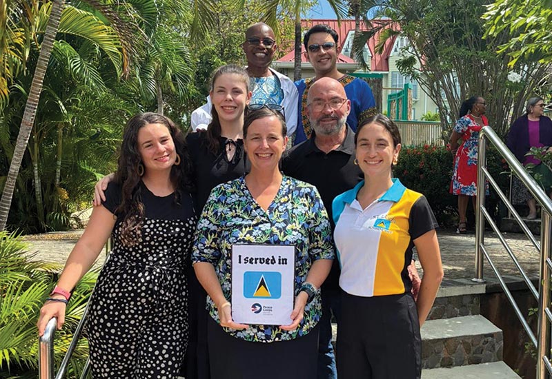 Amy Siegesmund and several other people standing on stairs and smiling while she served in St. Lucia during her Peace Corps trip