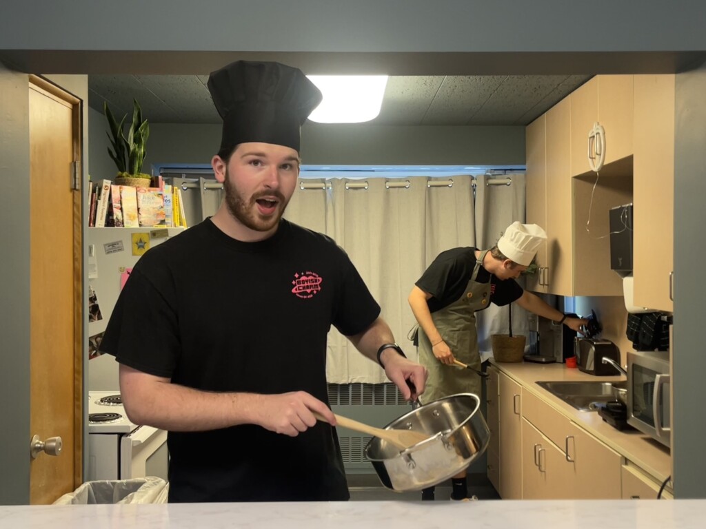 Two male students cook in a campus kitchen.