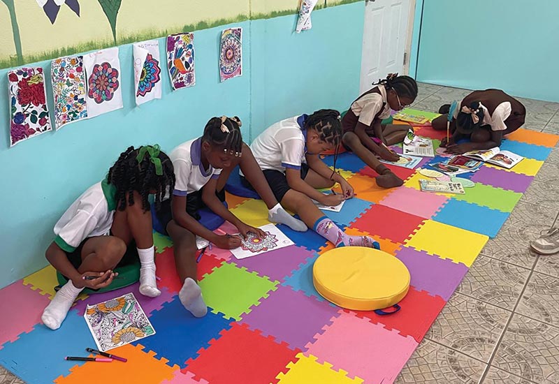 Students sitting and reading and coloring on the ground in a library