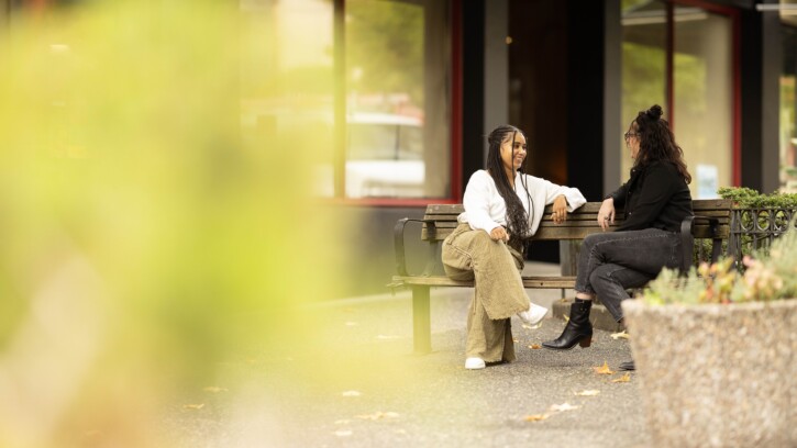 Two alumni from PLU's MFT program chat with each other on a park bench in downtown Tacoma.
