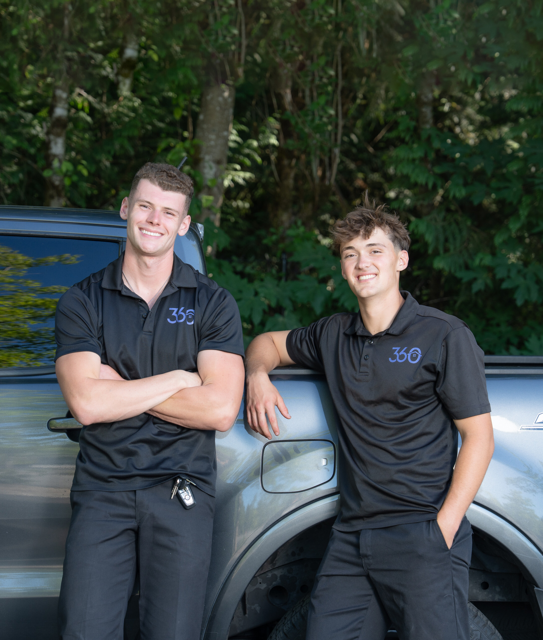 Two young men smile at the camera while wearing logo shirts from their company, 360 Home Services.