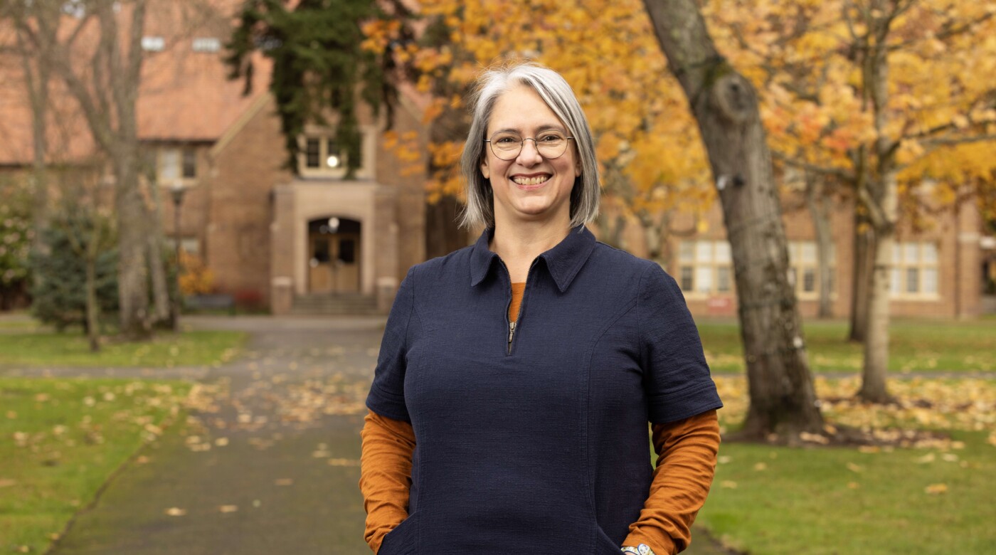 Rebekah M. K. Mergenthal smiles at the camera in front of Xavier on a fall day.