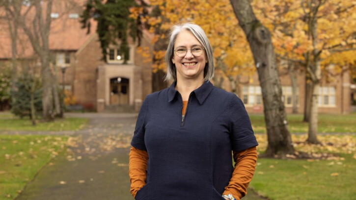 Rebekah M. K. Mergenthal smiles at the camera in front of Xavier on a fall day.