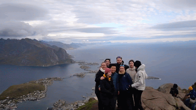 In this gif, a group of students pose at the summit of a mountain in the