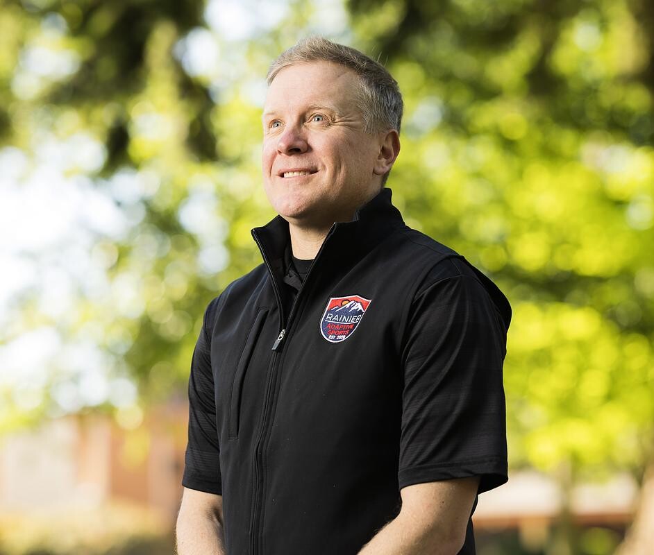 A middle-aged man wearing a black jacket outdoors.