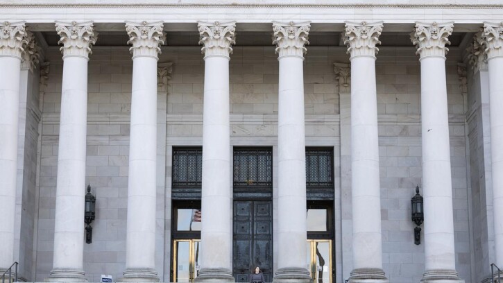 Student stands on the top steps of the Washington state capitol building.