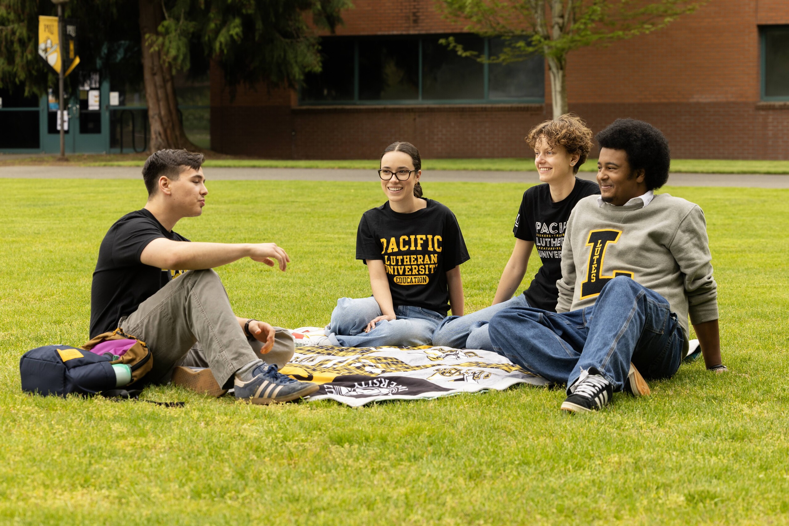 20260428_SB_Digital-Ads_076-full Four students sitting together on campus grass chatting