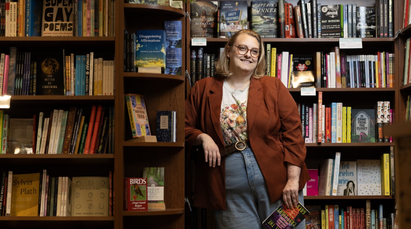 Alum Courtney Gould smiling in library surrounded by full bookshelves