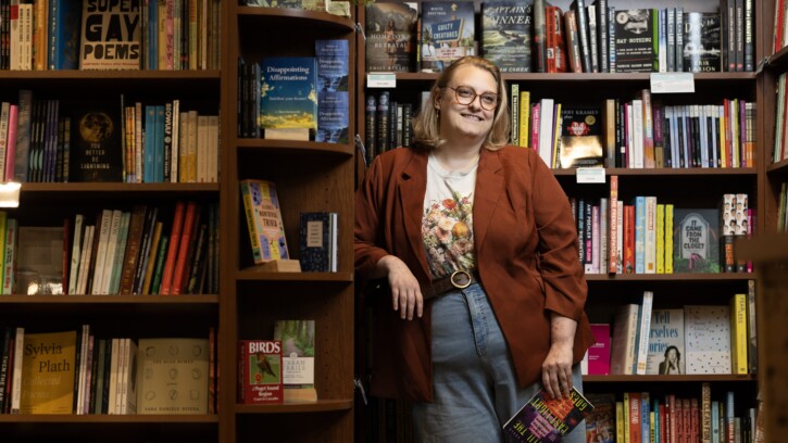 Alum Courtney Gould smiling in library surrounded by full bookshelves