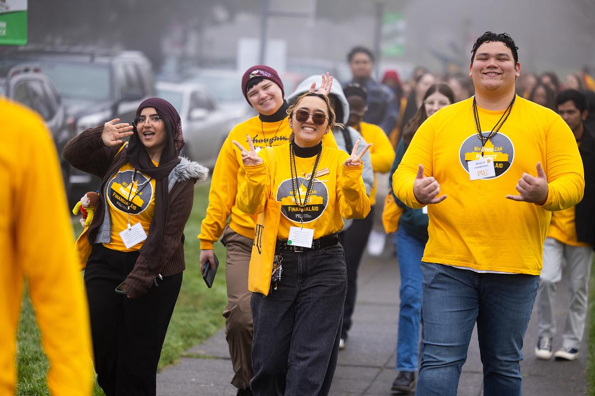 Group of smiling women and men wearing yellow shirts and medals at outdoor event