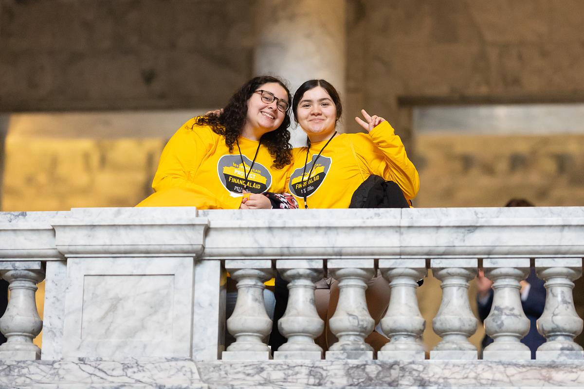 Two students stand on a balcony inside the Washington State Capitol building.