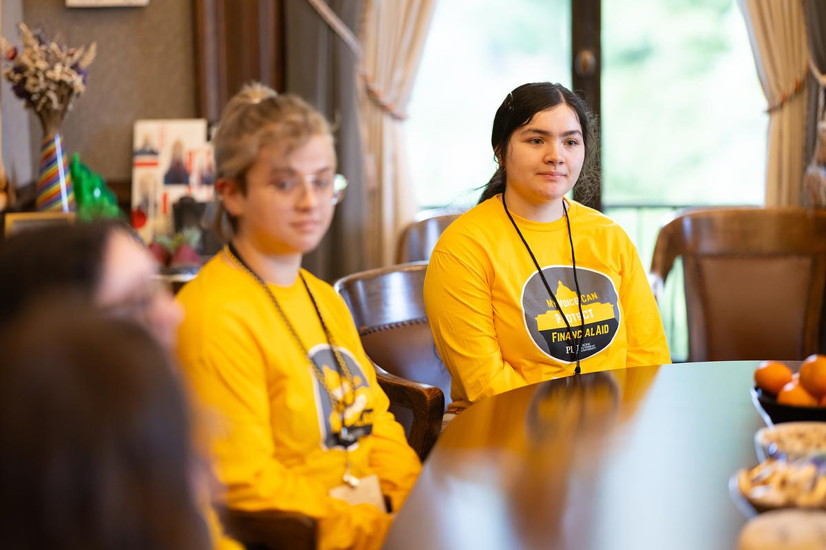 Two girls in yellow shirts at a conference table event
