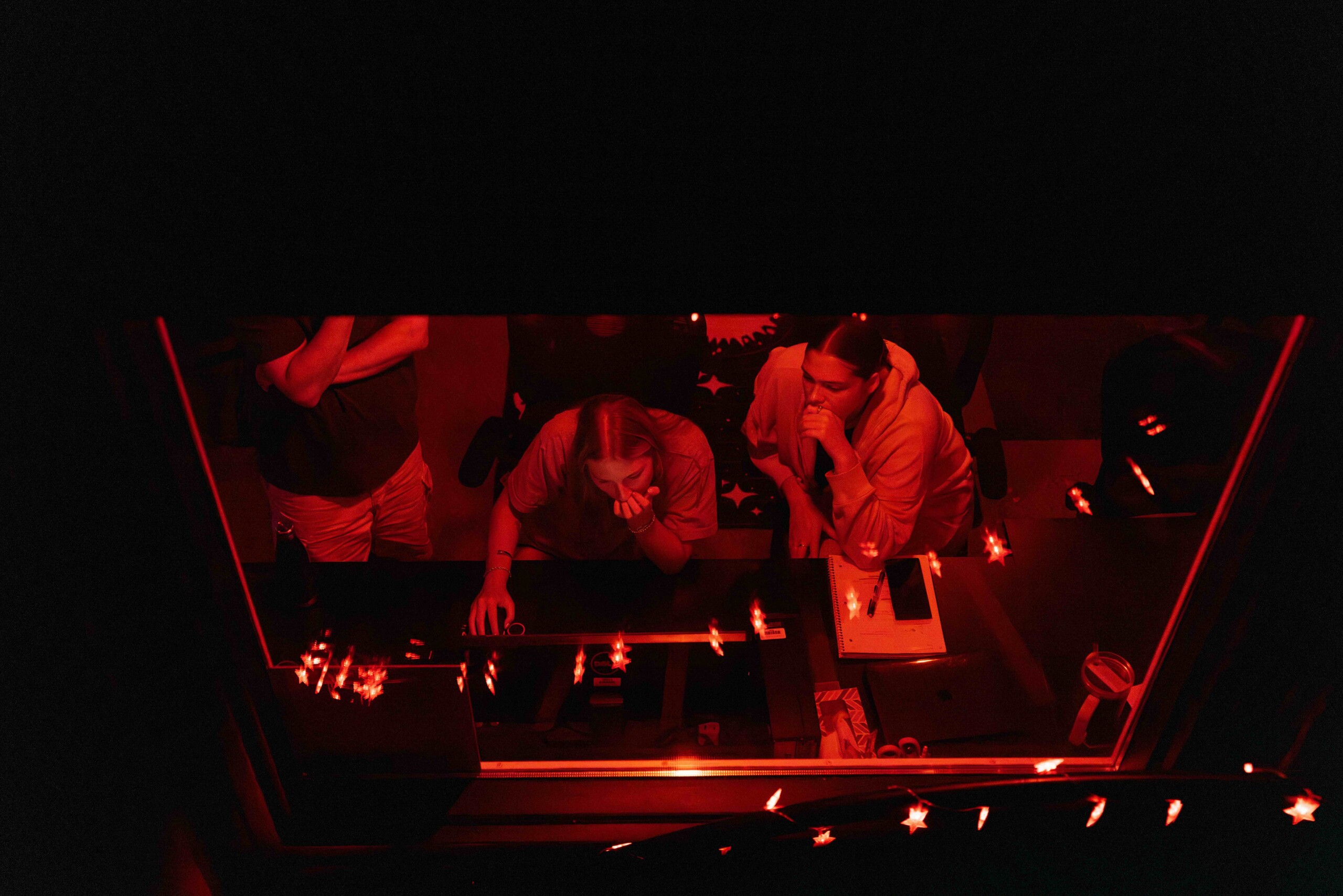 Three people work in red-lit darkroom during late night research in the Keck Observatory.
