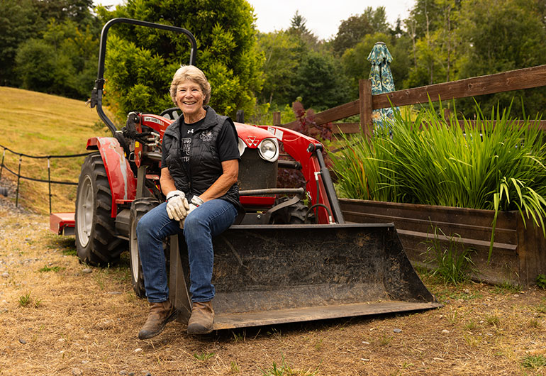 Assistant Softball Coach Cindy Van Hulle sitting on a red tractor.