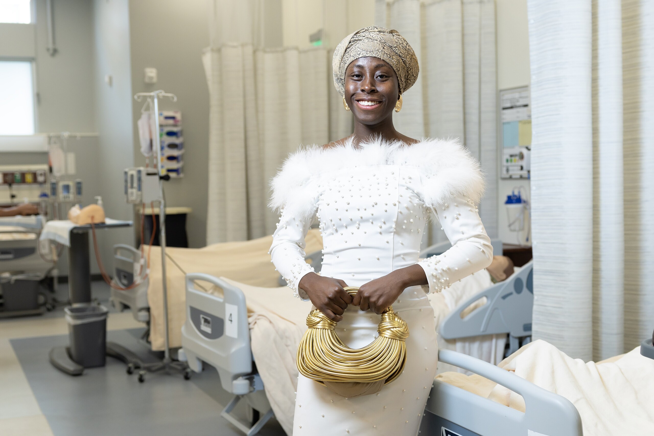 Hanot in elegant white dress smiling in hospital simulation room at PLU.