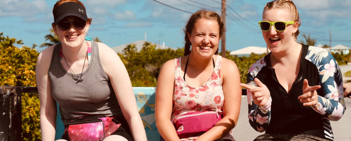 Three PLU students sit on the back of a truck in the Bahamas