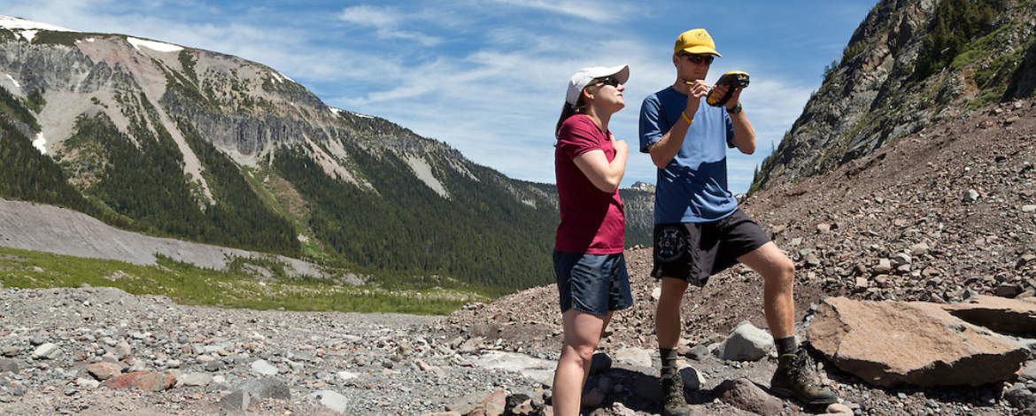 Two people stand in rock rubble at Mt. Rainier