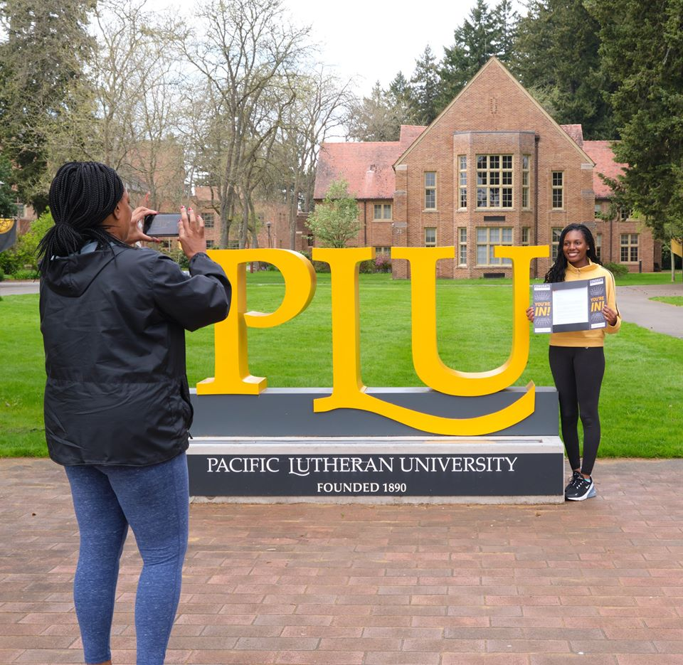 Student getting picture taken in front of PLU LUTE sign.