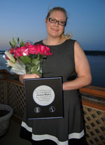 Amanda Mackey posing with award and holding flowers