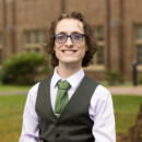 Andrew Caruana in formal vest and tie outdoors at campus
