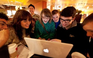 Group of smiling students around a laptop