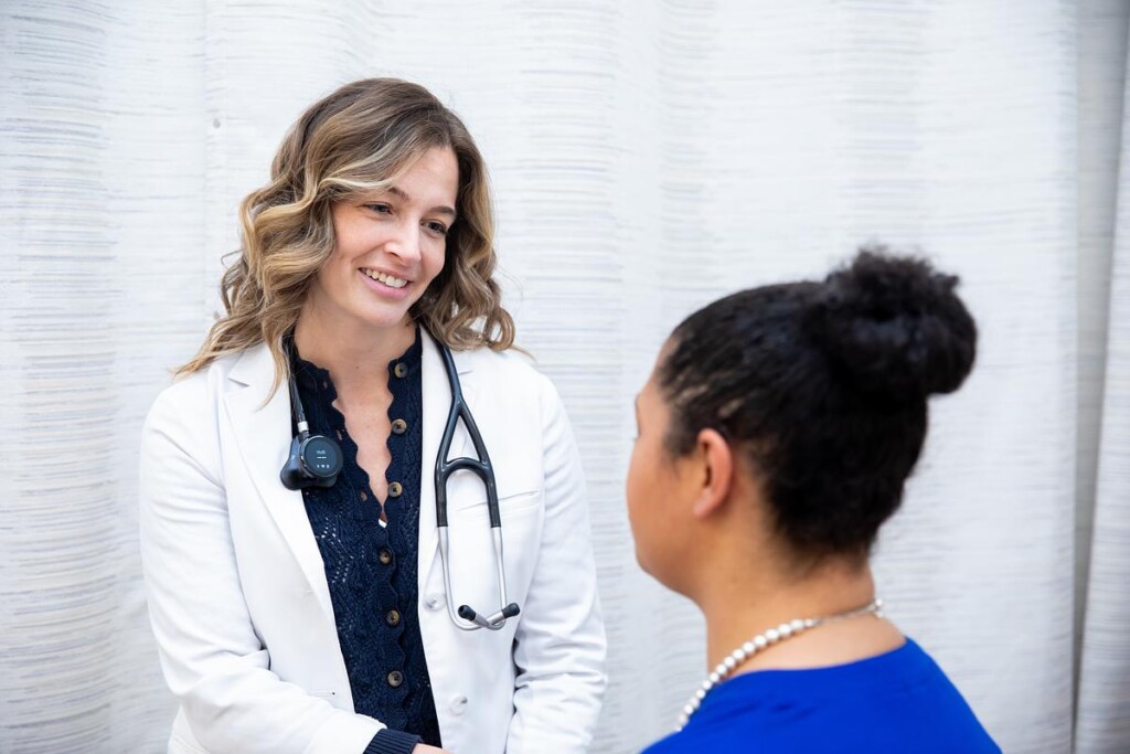 A doctor in a white coat speaking with a patient.