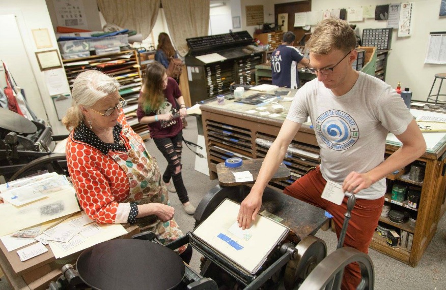 Mare Blocker teaching a student how to use the printing press