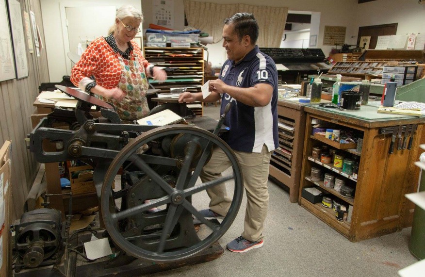 Mare Blocker teaching a student how to use the printing press
