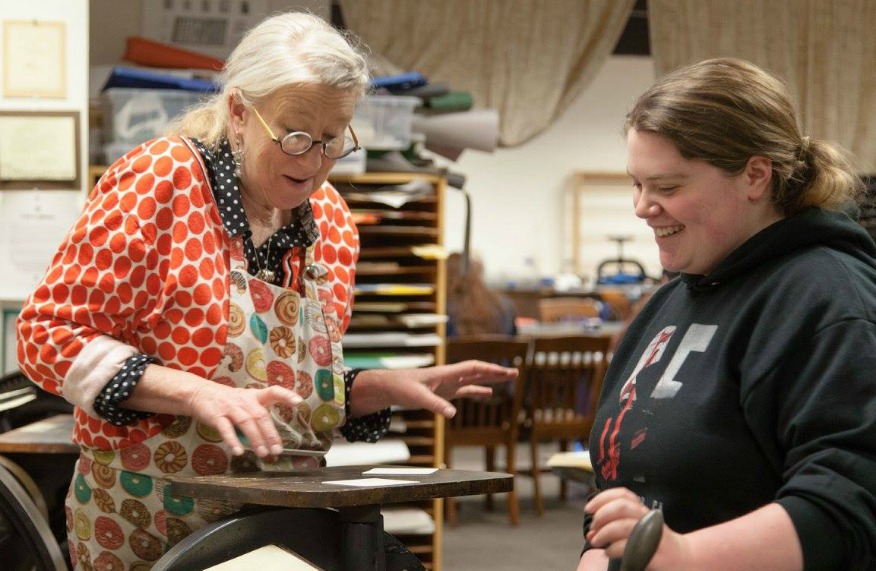 Mare Blocker teaching a student how to use the printing press