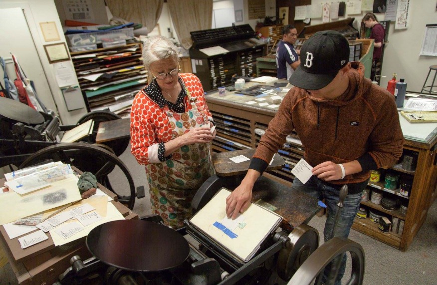 Mare Blocker teaching a student how to use the printing press