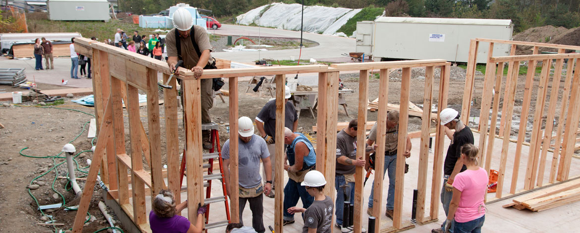 Volunteers, including some from PLU, secure and align a wall at a Habitat for Humanity build site in the Woods at Golden Given, a sustainable 30-home housing community. The house was built for a student who, at the time, was studying marriage and family therapy.