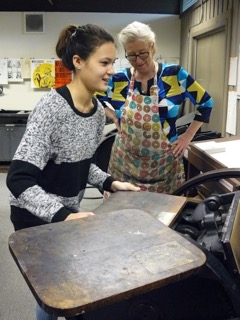 Student works with letterpress printer photo of student working on letterpress printer