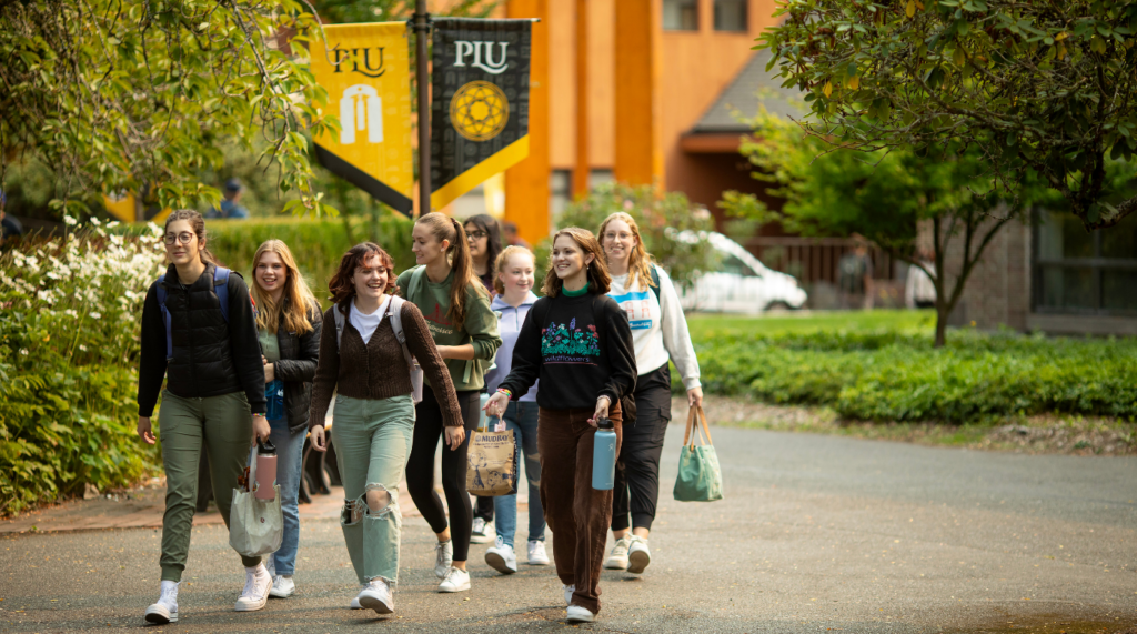recruit a lute Students walk on campus in a group. There are PLU banners in the background.