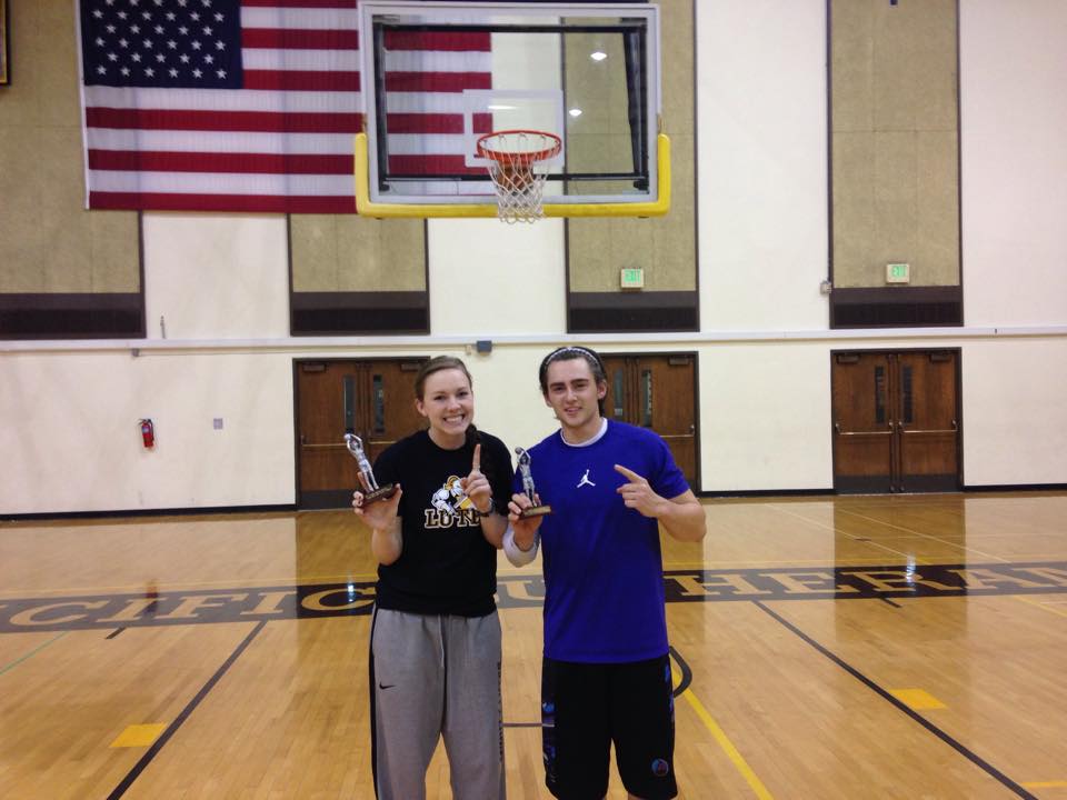 2 students posing with trophys in gym