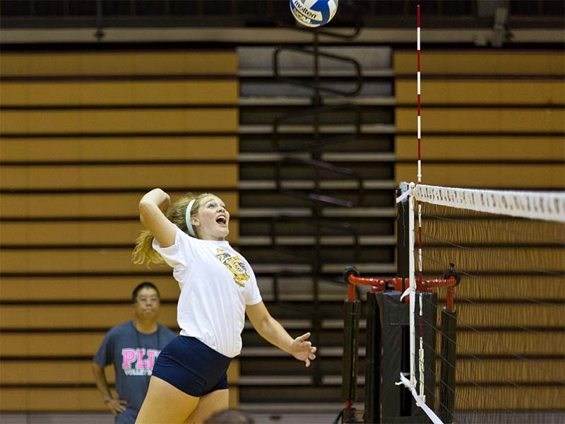 PLU volleyball player jumping up to spike a ball
