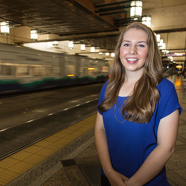 Anna Jessen poses in downtown Seattle tunnel with the Link light rail and busses