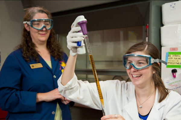 A PLU professor looks on as a student conducts an experiment