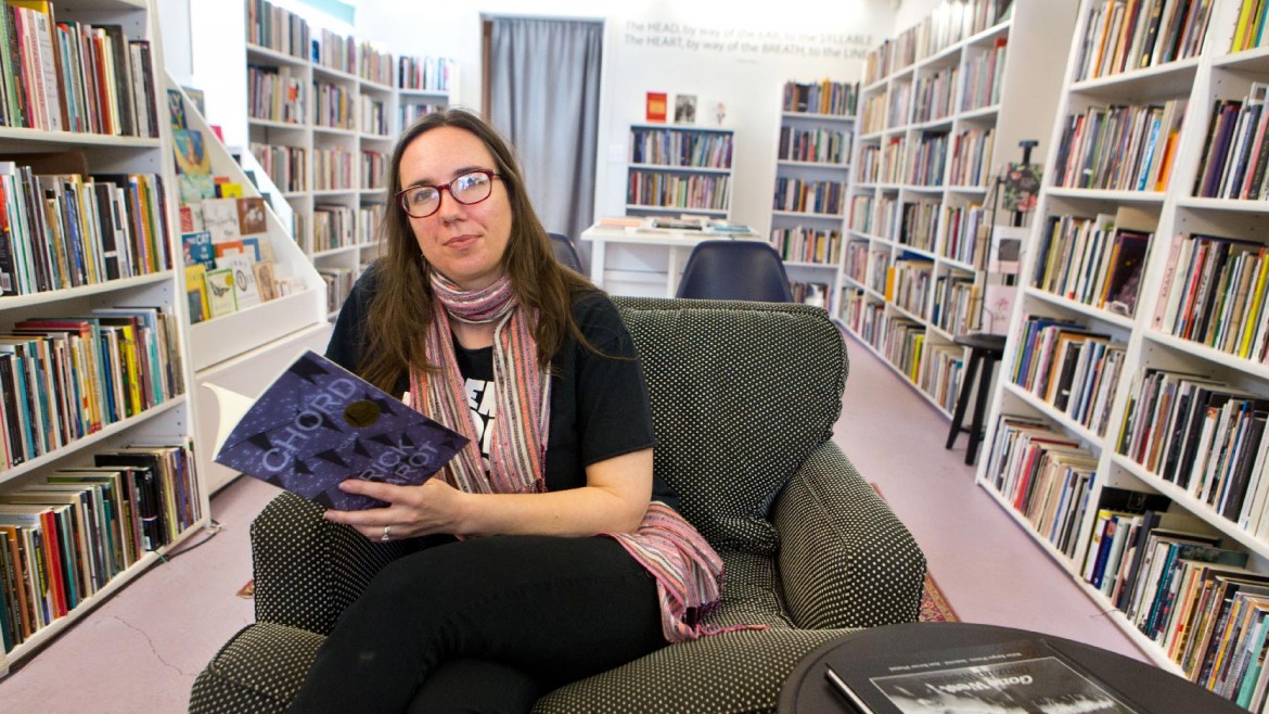 Billie Swift sitting and holding a book in a book store