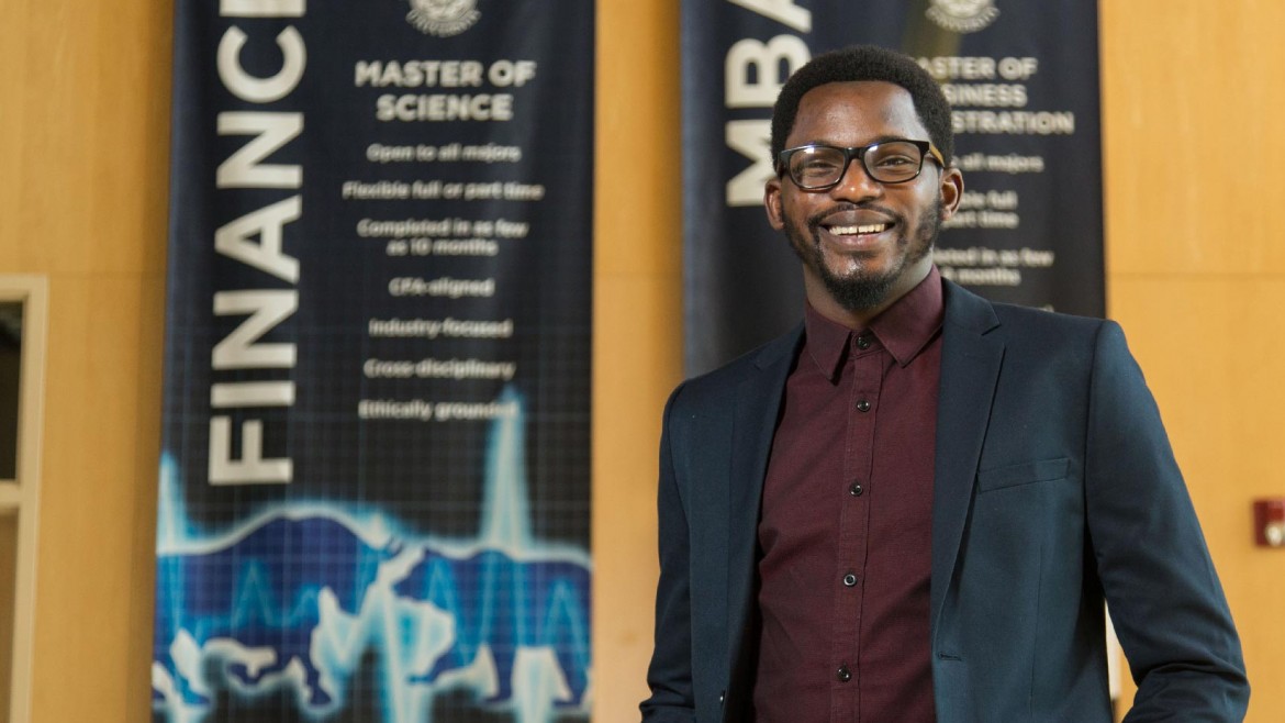 Pape Samba standing and smiling in front of MSF banners at PLU