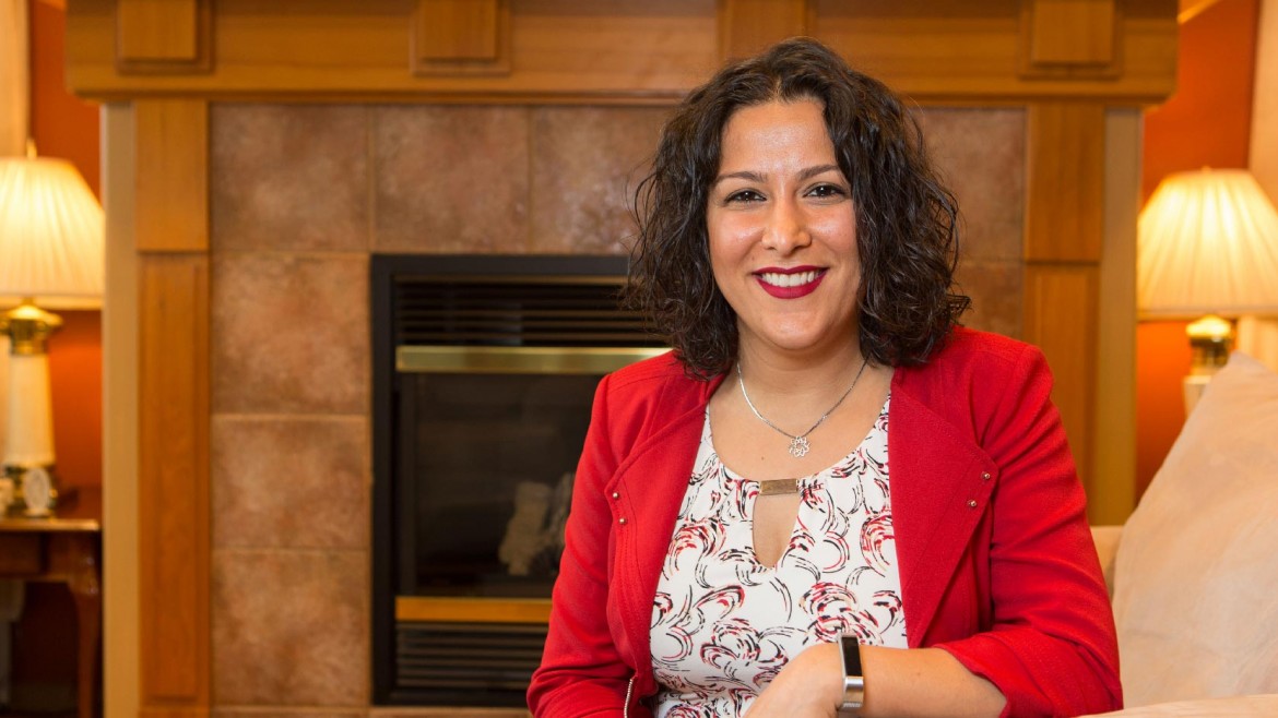 Shiva Sabet-Kazilas smiling while sitting in front of a fireplace