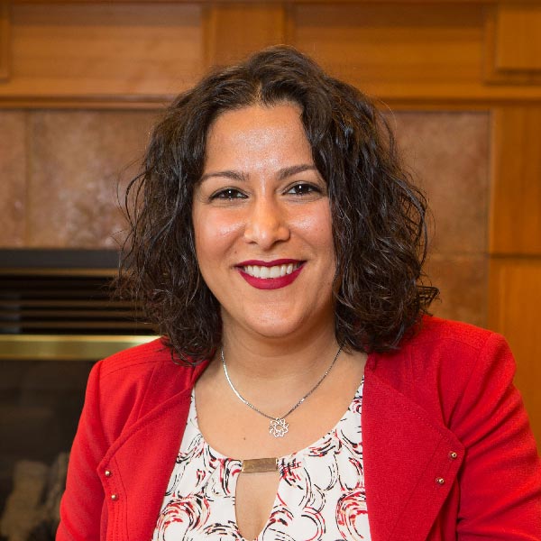 Shiva Sabet-Kazilas smiling while sitting in front of a fireplace